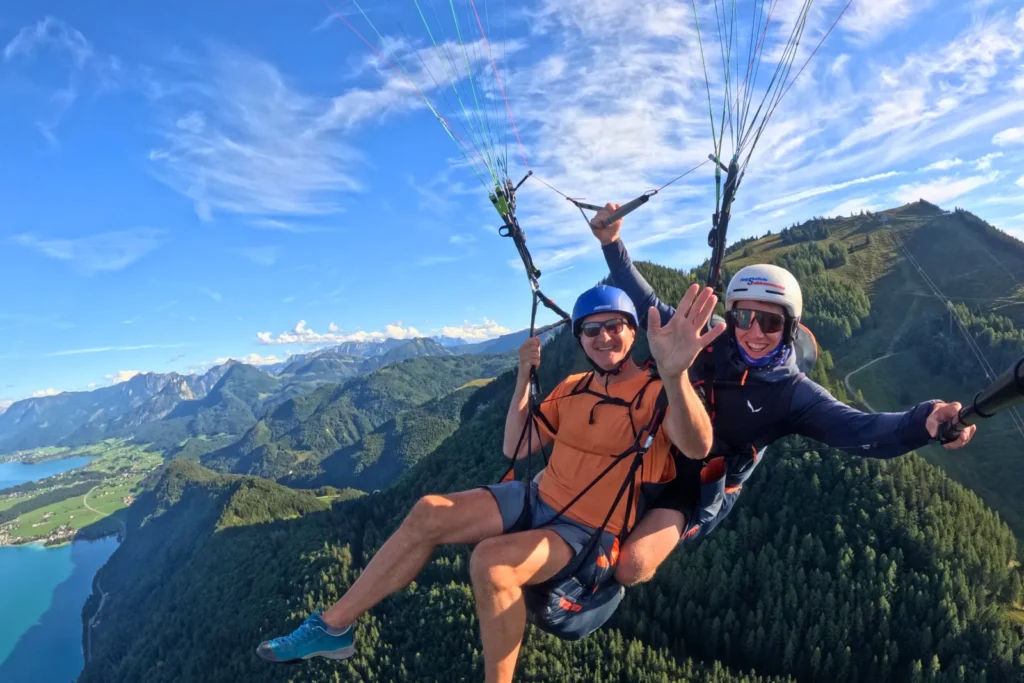 Passagier winkt beim Tandemflug – Paragleiten über dem Wolfgangsee im Salzkammergut