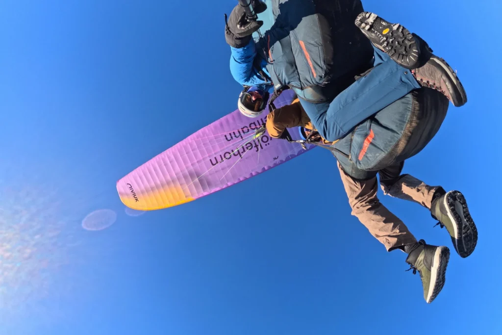 Dynamic aerial selfie looking up at the tandem paraglider during a paragliding flight at Gaisberg.