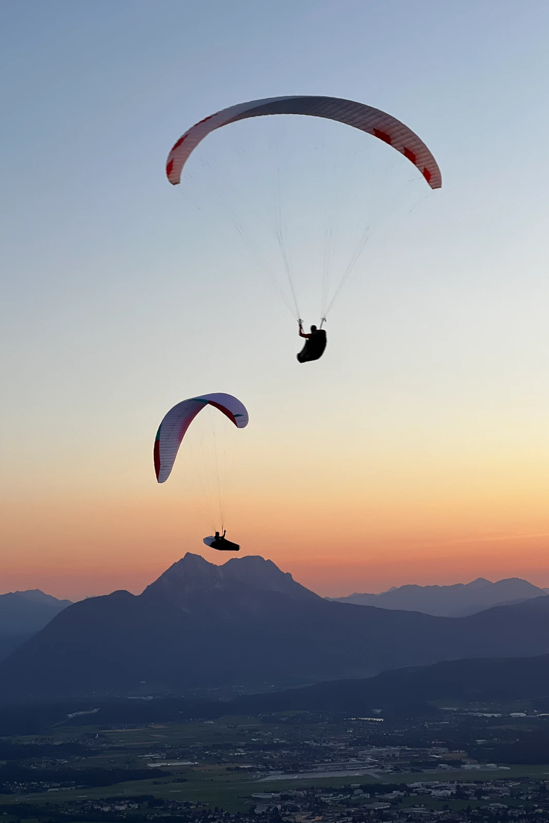 Zwei Gleitschirme im Sonnenuntergang über Berglandschaft