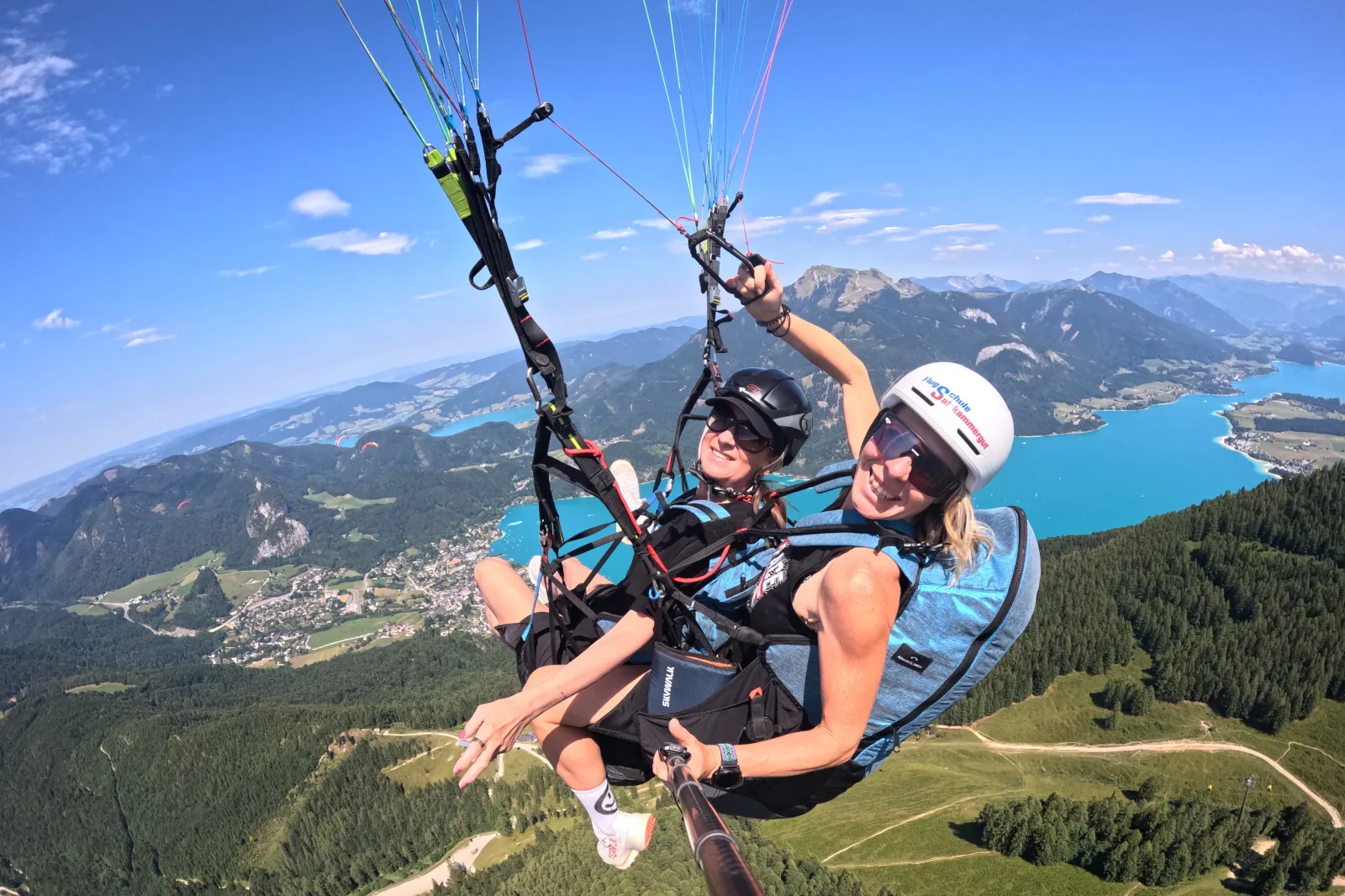 Julia and Erika toast with non-alcoholic sparkling wine during their tandem flight over Lake Wolfgang